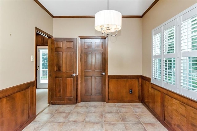 unfurnished room featuring an inviting chandelier, wooden walls, and ornamental molding