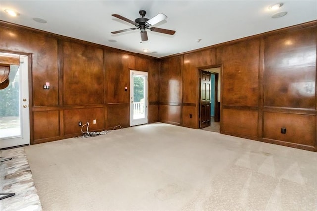 spare room with wooden walls, ceiling fan, and light colored carpet