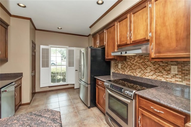 kitchen with appliances with stainless steel finishes, crown molding, backsplash, and dark stone counters