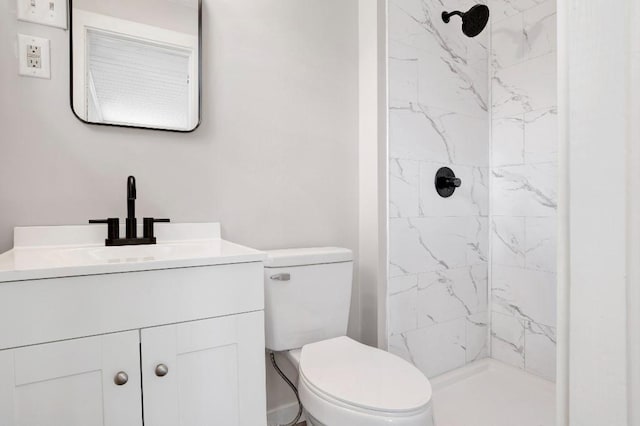 bathroom featuring vanity, a tile shower, and toilet