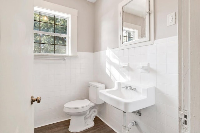 bathroom featuring hardwood / wood-style flooring, toilet, sink, and tile walls