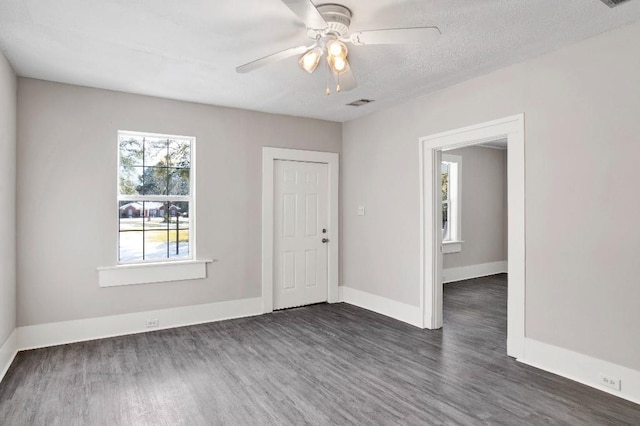 empty room with dark wood-type flooring, a textured ceiling, and ceiling fan