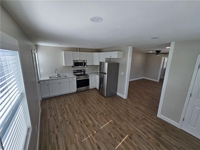 kitchen with appliances with stainless steel finishes, dark hardwood / wood-style floors, sink, white cabinets, and ceiling fan