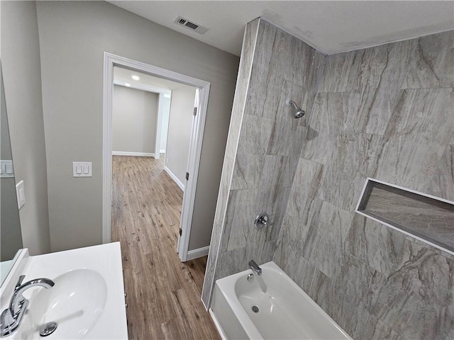 bathroom featuring tiled shower / bath combo, vanity, and hardwood / wood-style floors