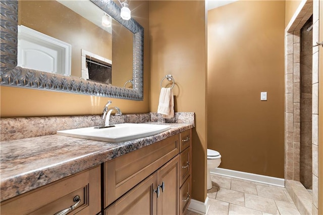 full bathroom with vanity, baseboards, a tile shower, and toilet