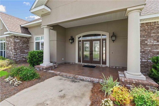 property entrance featuring a porch, a shingled roof, stucco siding, and french doors