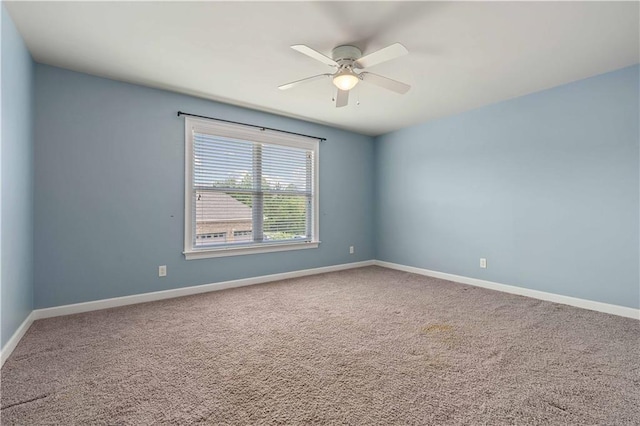 carpeted spare room featuring baseboards and ceiling fan