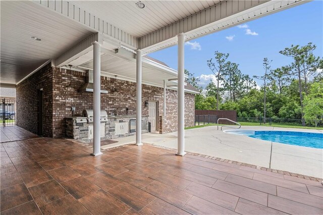view of pool featuring fence, grilling area, a patio, a fenced in pool, and exterior kitchen