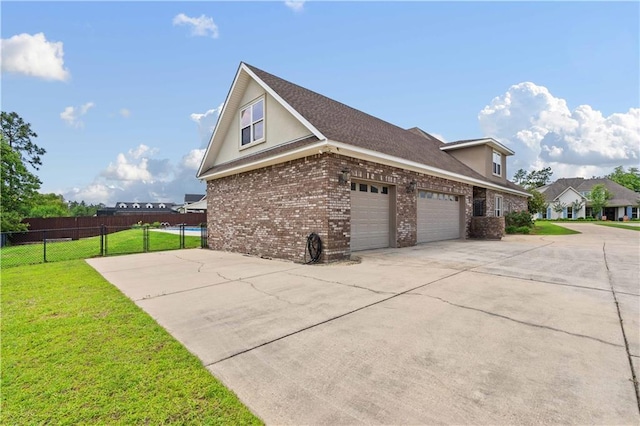 view of home's exterior with a yard, brick siding, an attached garage, and fence