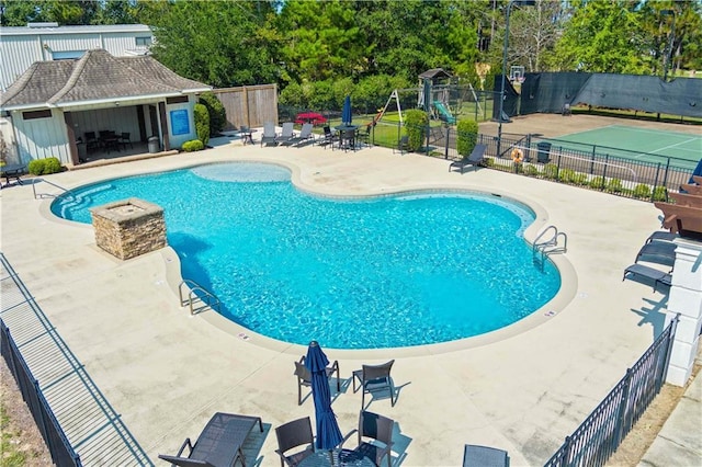 pool featuring fence, an outdoor structure, and a patio area