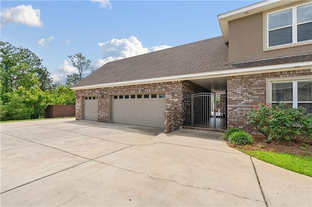 view of front of house featuring fence, a shingled roof, brick siding, a garage, and concrete driveway