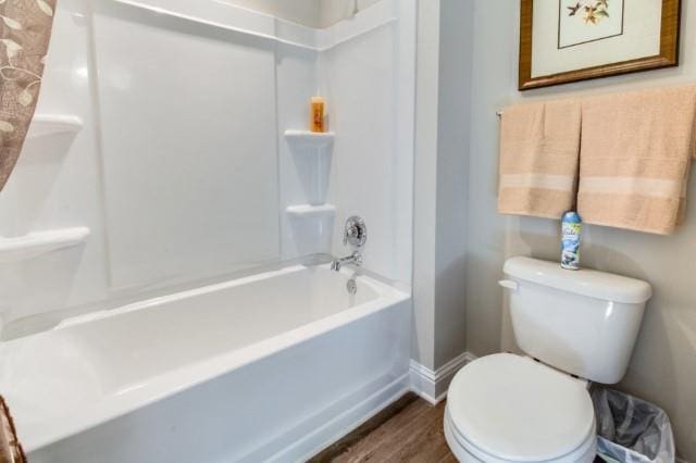 bathroom featuring hardwood / wood-style flooring, toilet, and bathing tub / shower combination