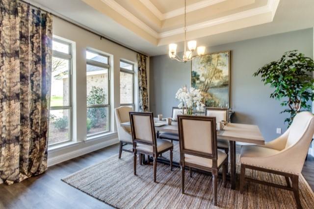 dining area featuring dark hardwood / wood-style flooring, crown molding, plenty of natural light, and a raised ceiling