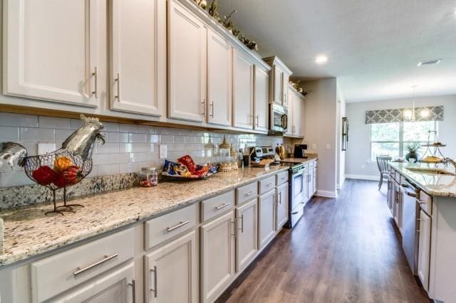 kitchen with white cabinetry, appliances with stainless steel finishes, light stone counters, and hanging light fixtures