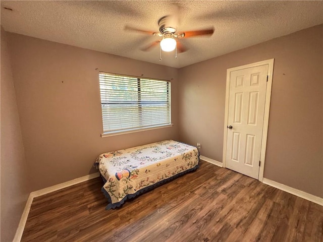 bedroom with a textured ceiling, ceiling fan, and dark hardwood / wood-style flooring