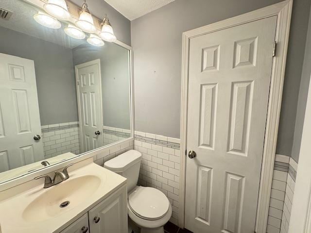 bathroom with vanity, toilet, and tile walls