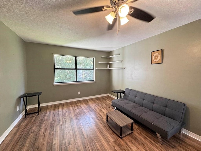 living room with ceiling fan, wood-type flooring, and a textured ceiling