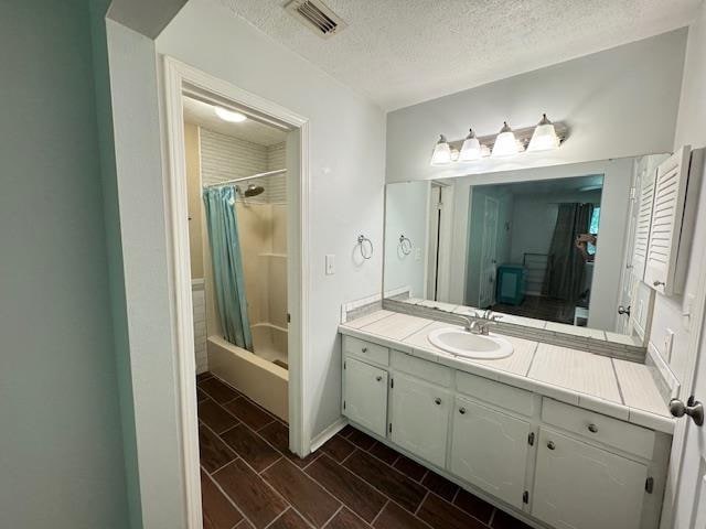 bathroom featuring shower / bath combo, vanity, and a textured ceiling