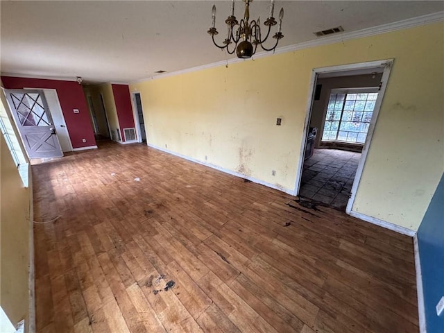 unfurnished living room with an inviting chandelier, hardwood / wood-style floors, and crown molding