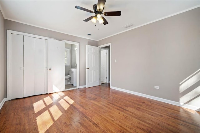 unfurnished bedroom featuring baseboards, visible vents, wood finished floors, and ornamental molding