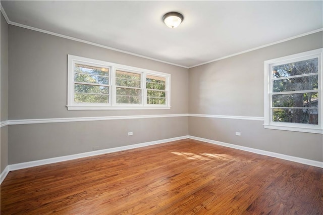 spare room with crown molding, baseboards, and wood finished floors