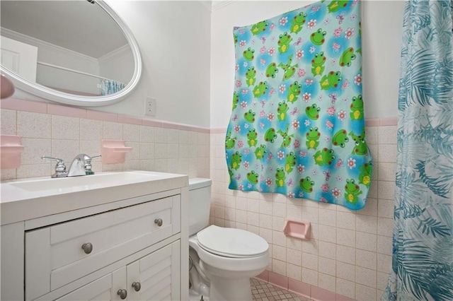 full bath with a wainscoted wall, tile walls, toilet, vanity, and tile patterned flooring