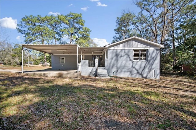 view of front facade featuring driveway, a front lawn, a carport, and brick siding