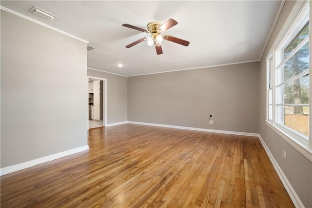 unfurnished room with ornamental molding, wood finished floors, visible vents, and baseboards