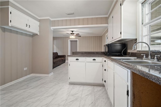 kitchen with visible vents, dark countertops, a peninsula, white cabinetry, and a sink