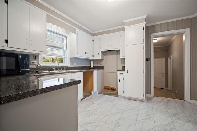 kitchen featuring marble finish floor, crown molding, a sink, dark stone counters, and black microwave