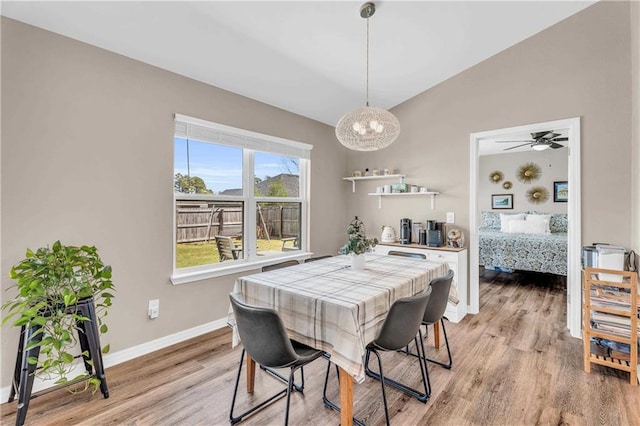 dining space featuring baseboards, lofted ceiling, light wood-style flooring, and ceiling fan with notable chandelier