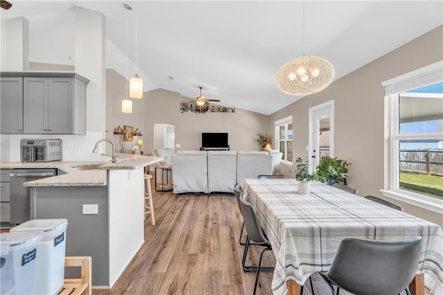 dining room featuring a wealth of natural light, lofted ceiling, light wood finished floors, and ceiling fan with notable chandelier