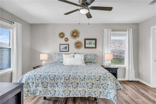 bedroom featuring ceiling fan, visible vents, baseboards, and wood finished floors