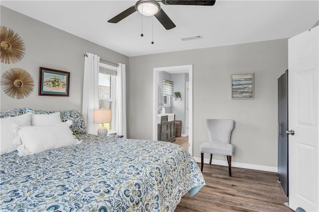 bedroom with visible vents, connected bathroom, ceiling fan, baseboards, and wood finished floors