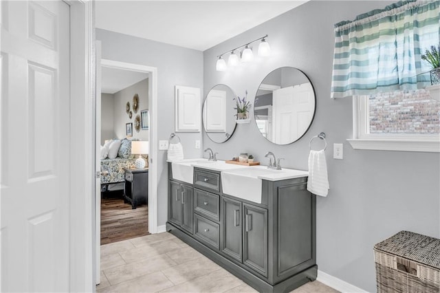 full bathroom featuring double vanity, baseboards, ensuite bathroom, and a sink