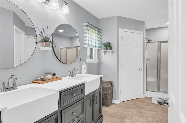 bathroom with double vanity, a stall shower, and a sink