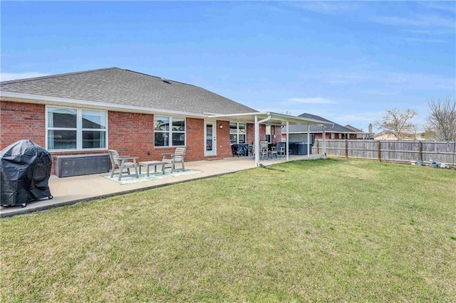 rear view of house featuring a patio area, a yard, fence, and brick siding