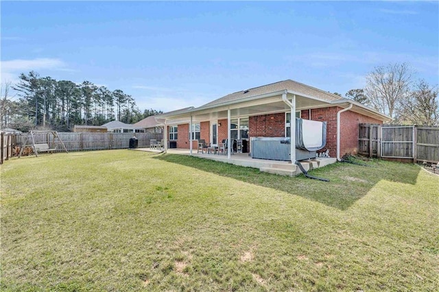 rear view of house featuring a patio area, a yard, a fenced backyard, and brick siding