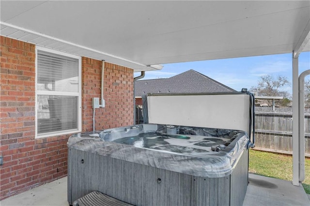 view of patio featuring a hot tub and fence