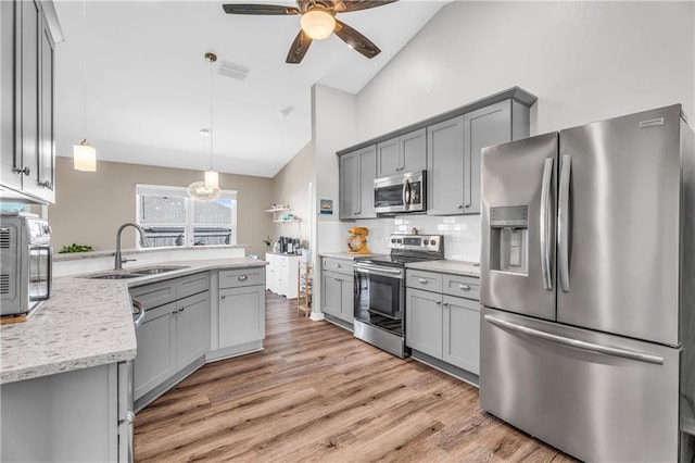 kitchen featuring light wood finished floors, gray cabinetry, stainless steel appliances, a ceiling fan, and a sink