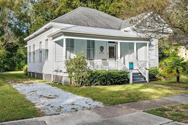 view of front of property featuring driveway, metal roof, roof with shingles, covered porch, and a front lawn