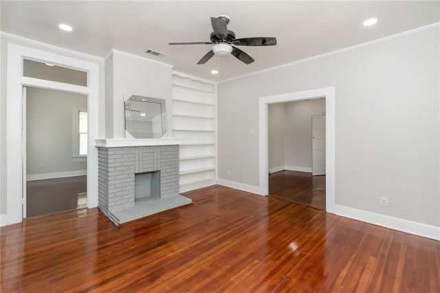 unfurnished living room featuring ornamental molding, a brick fireplace, built in shelves, wood-type flooring, and ceiling fan