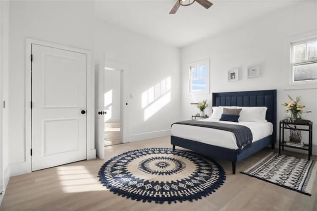 bedroom featuring multiple windows, light hardwood / wood-style floors, and ceiling fan