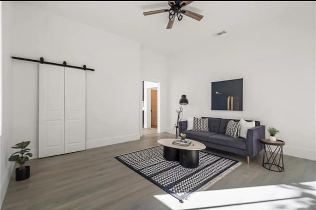 living room with a barn door, ceiling fan, and wood-type flooring