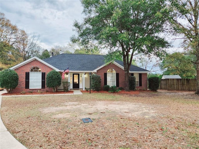 ranch-style home with brick siding, fence, and roof with shingles