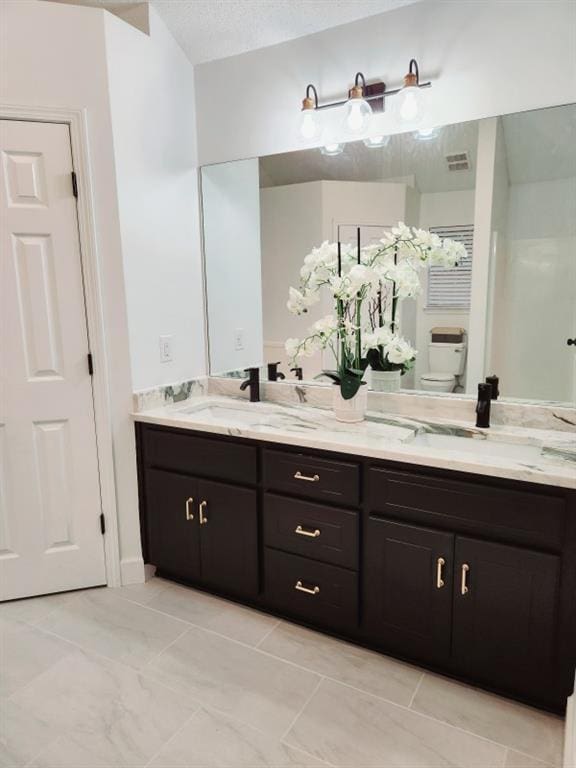 bathroom with vanity, a textured ceiling, and toilet