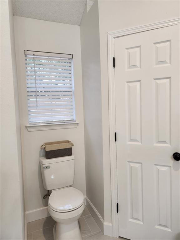 bathroom featuring tile patterned flooring, a textured ceiling, and toilet