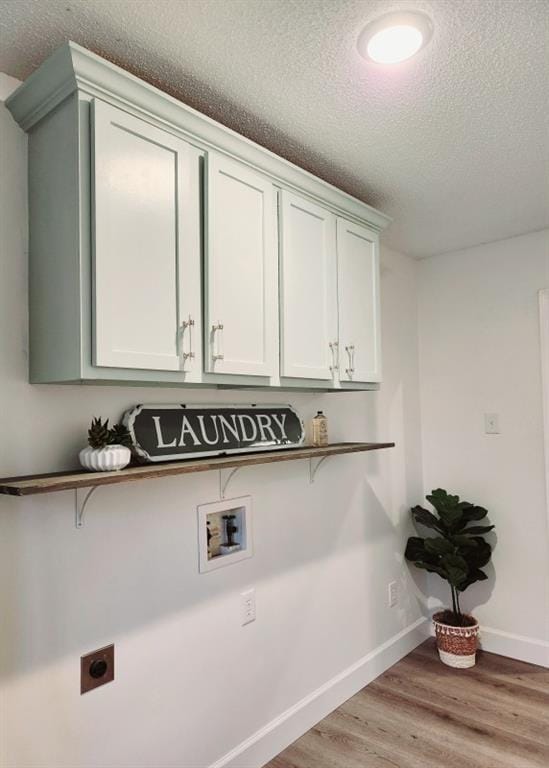 laundry room with cabinets, a textured ceiling, hookup for a washing machine, hookup for an electric dryer, and light hardwood / wood-style floors