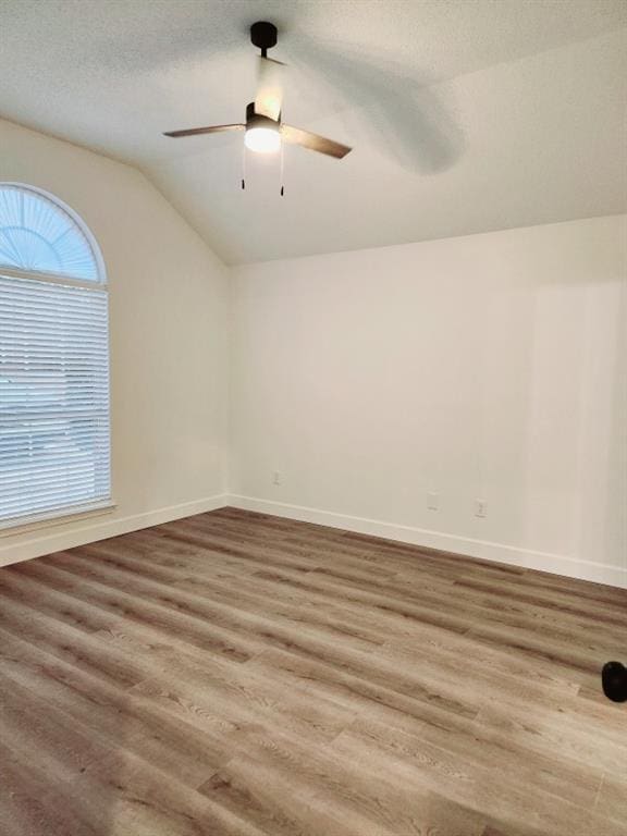 unfurnished room with hardwood / wood-style flooring, ceiling fan, vaulted ceiling, and a textured ceiling