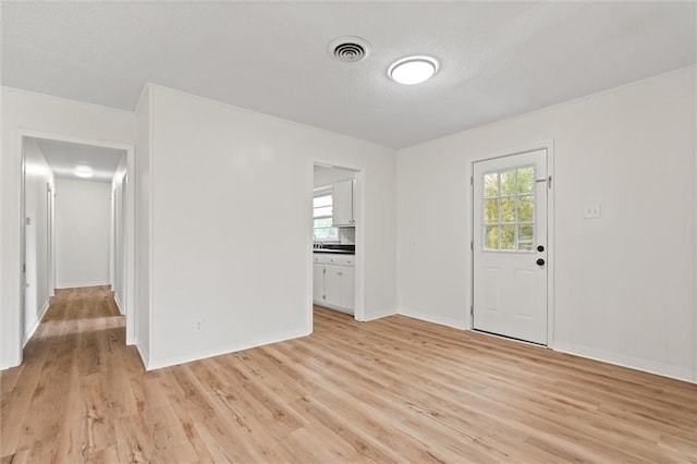 empty room featuring a textured ceiling and light wood-type flooring